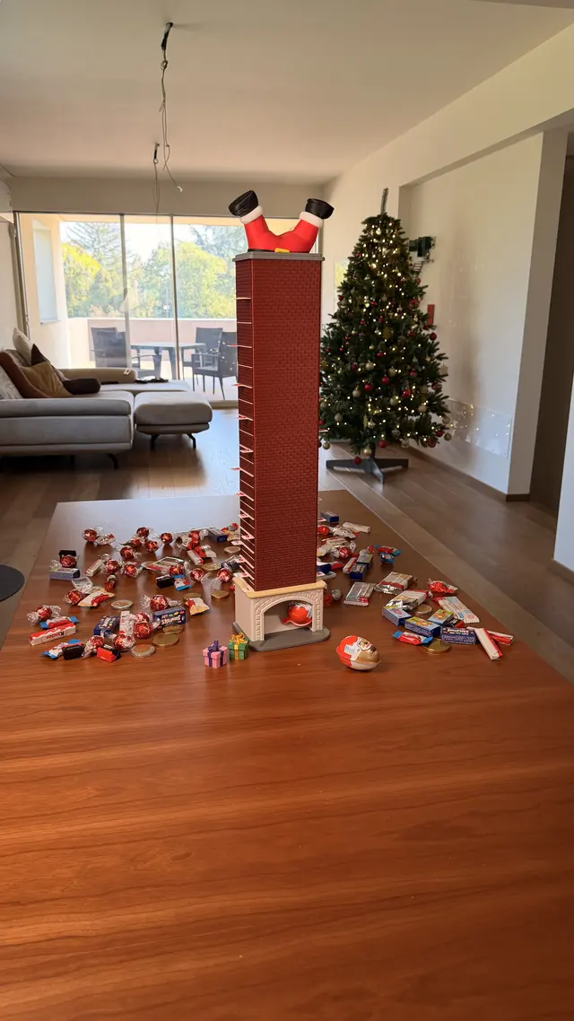 Il camino montato accanto all'albero di Natale, con Babbo Natale a testa in giù in cima e i dolcetti sul pavimento