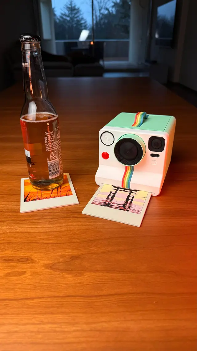 La fotocamera Memories Coasters sul tavolo con una bottiglia sul sottobicchiere