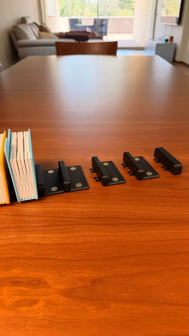 Pezzi della base nera separati, con i magneti rotondi e le clip di giunzione, accanto a due album